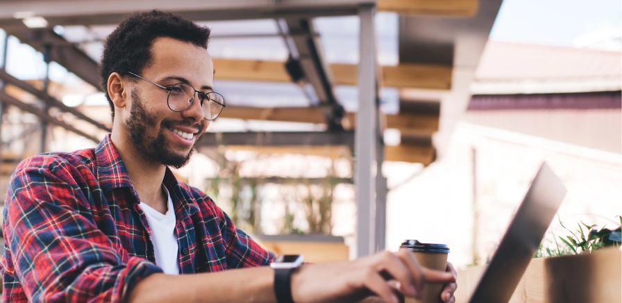 Homem negro com notebook tomando café